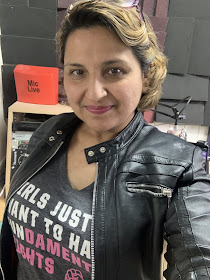 Woman in leather jacket in radio studio looking into camera 