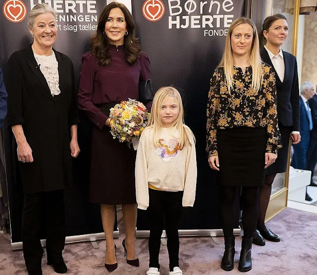 Crown Princess Mary presented research awards of Danish Heart Association. Mary wore a burgundy silk blouse and skirt