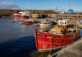 Photo of colour coordinated boats at Maryport Marina with MV Achiever in the distance