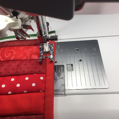 Sewing the binding on a red quilt by machine