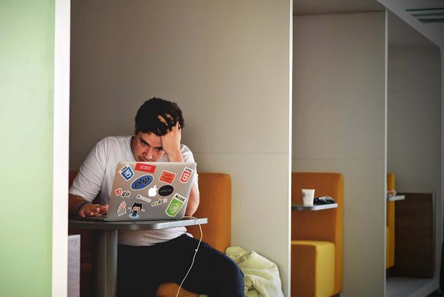 Why online education is not the future of education ? - Boy placing one hand on his head and using laptop