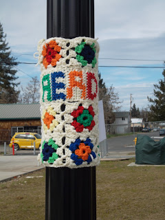 Yarnbombing tag: granny squares with panel that says "READ"