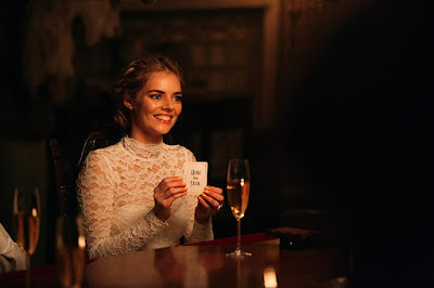 Movie still for the 2019 thriller Ready or Not where Samara Weaving's character Grace holds up a Hide and Seek playing card and seals her fate