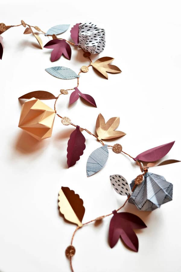 autumn-tone paper garland of origami baubles, glitter dots, and sculpted leaves