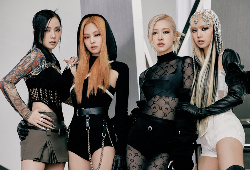 Blackpink posing together in black outfits, in front of metallic structures. [From Left to Right: Jisoo, Jennie, Rosé, Lisa]