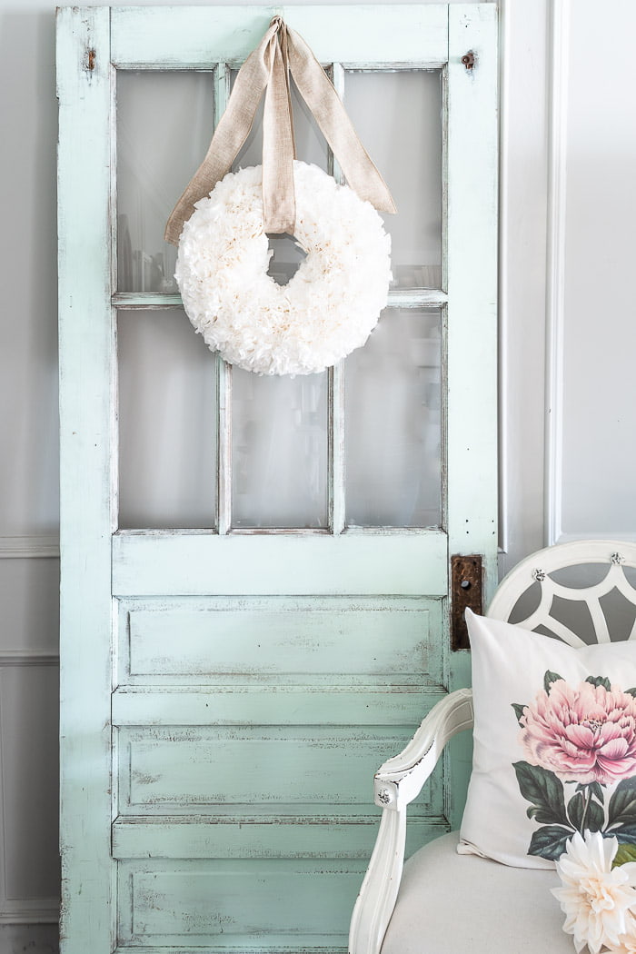 white wreath on chippy mint door, white chair, cottage pink pillow