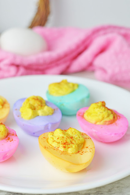 Dyed Deviled Eggs on a white plate with a pink napkin on the side.