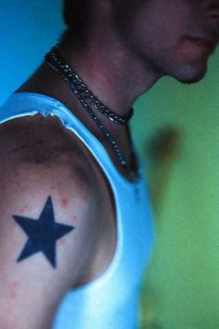 Black and white photo of a man's calf with simple star tattoo