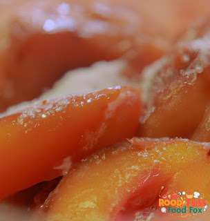  A picture of sliced peaches being coated in sugar mixture 