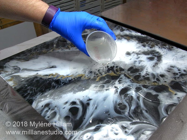 Applying a top coat of clear resin to the canvas.