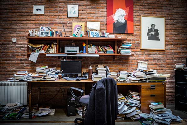 escritorio de horacio gonzalez repleto de papeles, libros, anotadores, revistas, un monitor y el mate