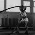 Grayscale photo of a woman using battle ropes