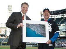 NASA astronaut Dr. John Grunsfeld presents a photo of Chicago from space to management at the White Sox game during the 2009 Hometown Heroes campaign in Chicago