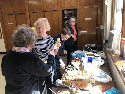 4 women are organizing the table of foods for the church potluck.