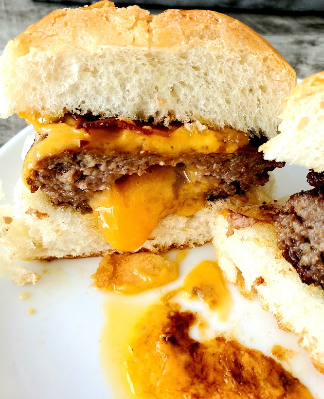 ground beef molded into a burger stuffed with extra sharp cheddar and oozing out the front