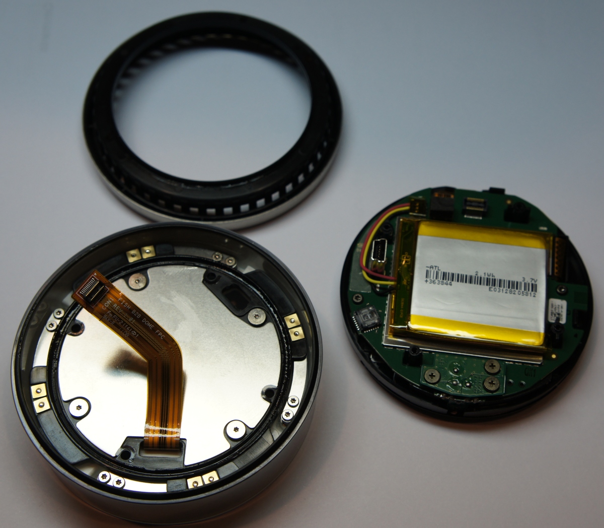 A close-up of a Nest Thermostat with the battery compartment open, showing the battery inside.