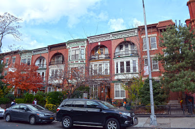 Row of several similar red brick row houses with loggias