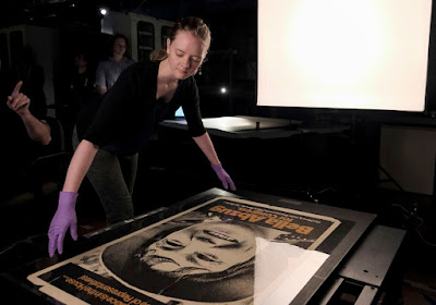 Amelia Brookins, object handler, arranges a poster of Bella Abzug to be photographed at the Smithsonian National Museum of American History.