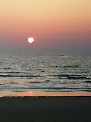 Sonnenuntergang am Meer,  vorne ist ein kleines Boot