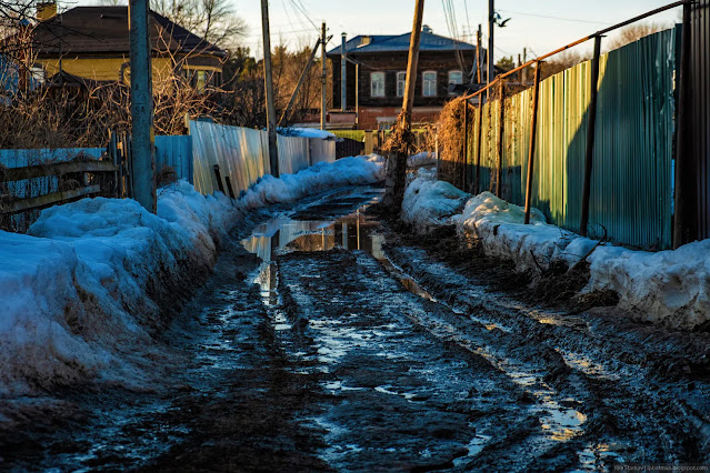 Дорога в поселке в грязи и лужах