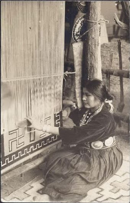 Native American woman weaving a rug with swastikas.