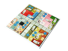 na zdjęciu plansza od gry patchwork a na niej ułożone w rogach cztery jednakowe kwadraty stworzone z elementów gry