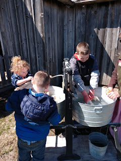 three children rub towels with lye soap at an old fashioned washboard at the Ingalls Homestead