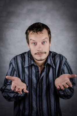 man in stripes shrugs and looks confused