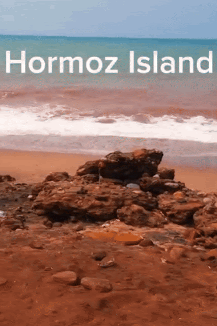 Animated view of the red soil beach and waves gently crashing on the shore of Hormoz Island in Iran, with text "Hormoz Island" at the top.