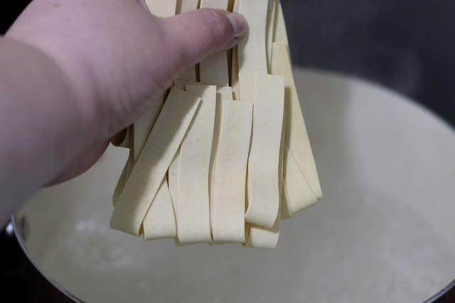 The pasta being added to the boiling water on the stove.