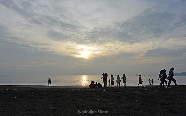 Pengunjung menikmati waktu pagi di pantai bersama keluarga