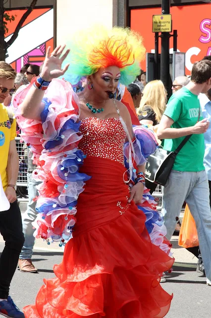 A man in drag (red ball gown and union jack boa) taking part in the 2015 London Pride procession