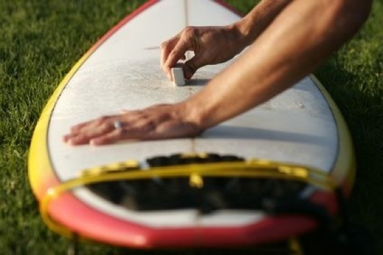 Girl waxing a surfboard