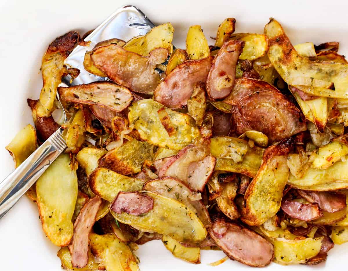 Roasted Fingerling Potatoes with Shallots and Rosemary close up with a spatula.