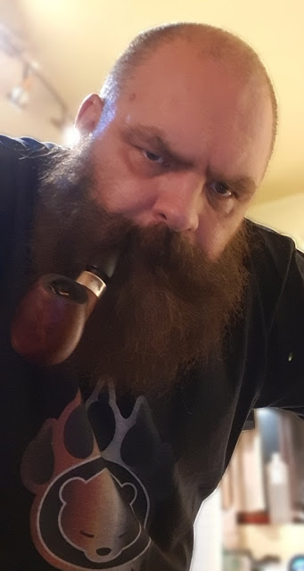 From chest up burly long-bearded tough daddy smoking pipe up close