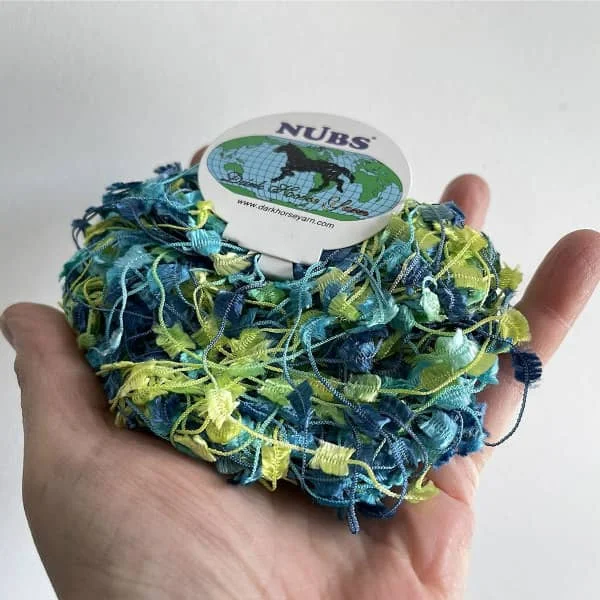 open hand palm displaying blue and yellow butterfly art fiber yarn