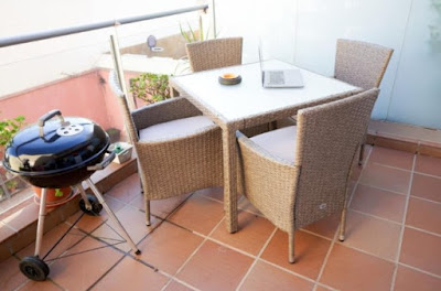 una terraza con una mesa cuatri sillas y una pequeña barbacoa en un apartamento de mataro