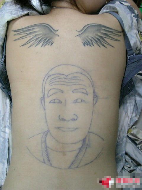 back wings tattoo and a head portrait tattoo
