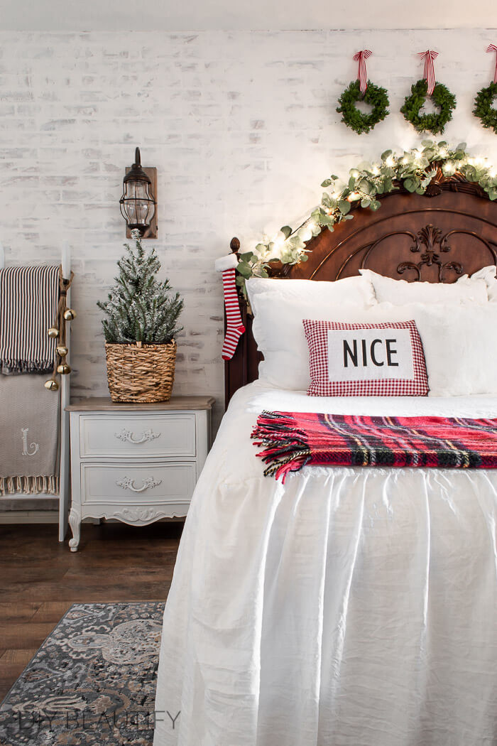 Christmas bedroom white linens, plaid, basket, tree, white brick wall