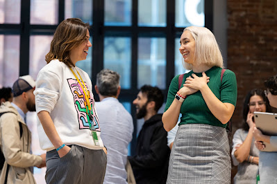 Dos personas jóvenes conversan en una oficina.