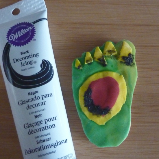 adding black decorating squeeze tube icing onto Halloween cookies