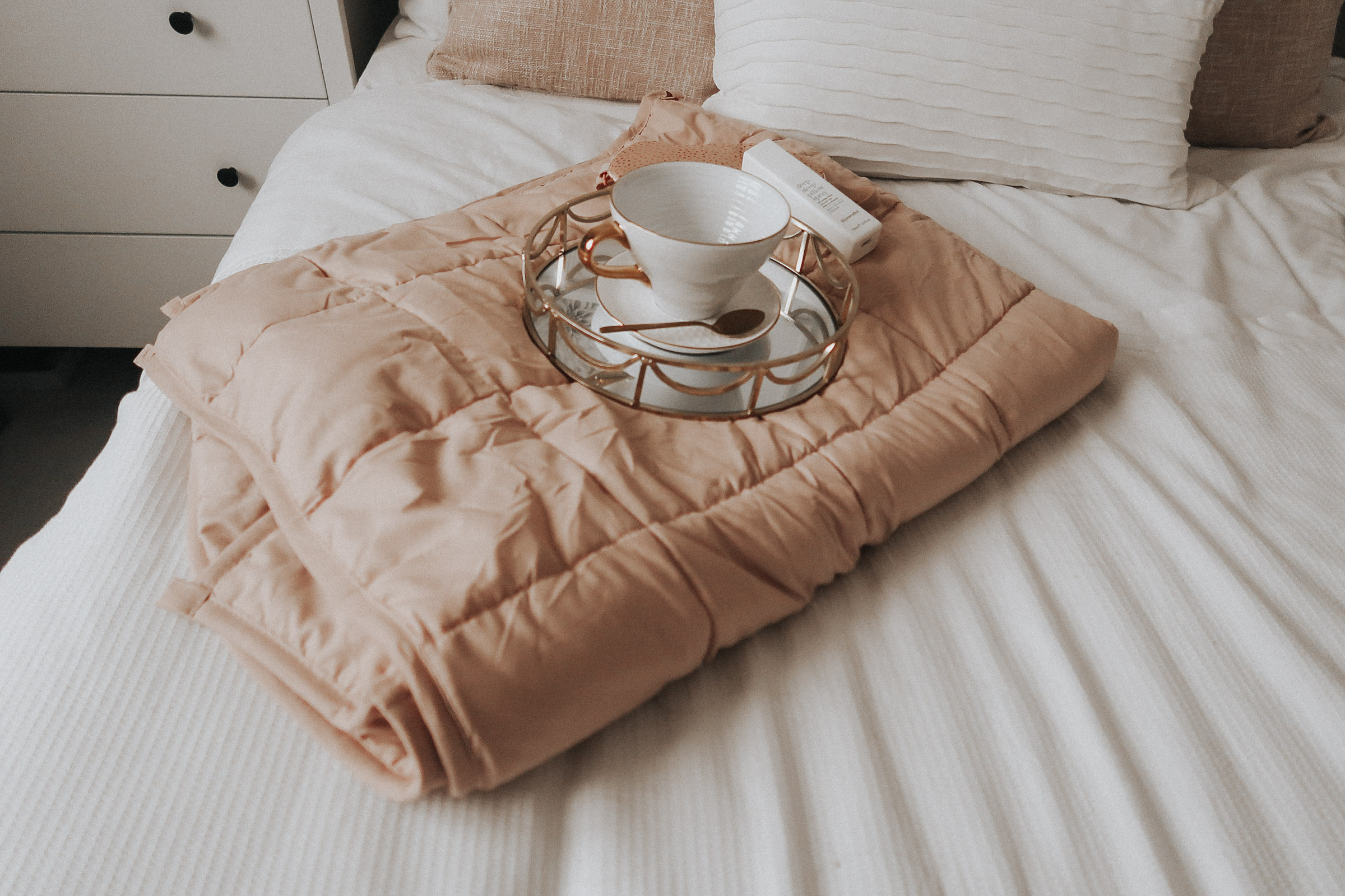 A pink weighted blanket on a bed.