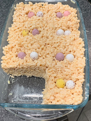 Mini Eggs Marshmallow Crispy Treats in a glass dish, cut into sections with one removed