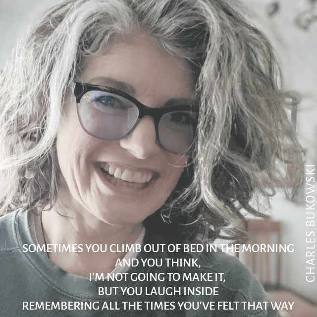 A woman with unruly hair and tape-repaired glasses smiles. The text reads "Sometimes you climb out of bed in the morning and you think, I'm not going to make it, but you laugh inside — remembering all the times you've felt that way.”  ― Charles Bukowski"