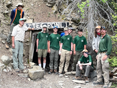 Group of Boy Scouts standing outside of an entrance to a mine with a sign reading Aztec Ponil 1