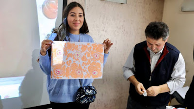 Une des participants montre le résultat du atelier ebru.