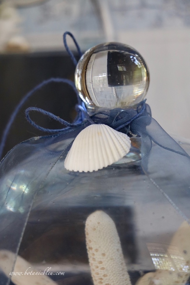 A single white shell tied with navy twine at the top of cloche adds coastal design for summer