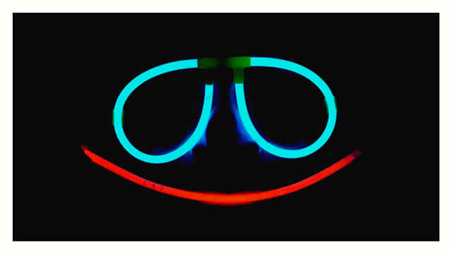 Imagen decorativa, lentes neon sobre fondo negro tomado del video de Layla Roots