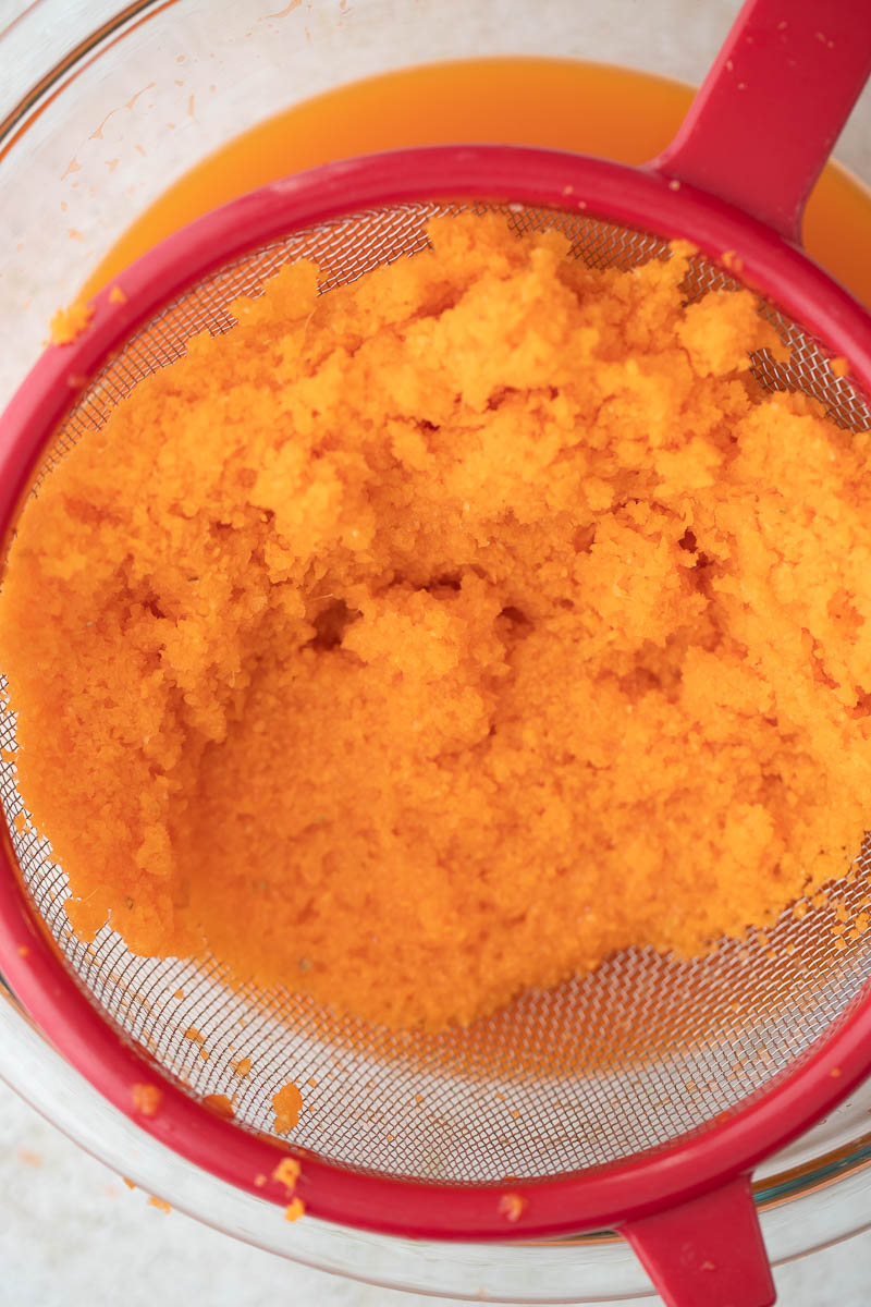 Ground up carrot pulp in a fine sieve about to be squeezed to get juice.