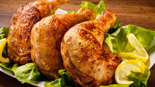 افخاذ دجاج مشوية في طبق تقديم مع خس وشرحات ليمون
